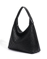 The Siren Woven Bag in black, three-quarter studio view showing the woven body and knotted strap