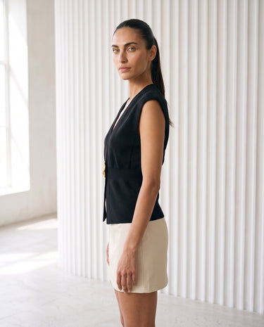 The Solara Gold Button Vest in black — sleeveless knit vest, side view on model