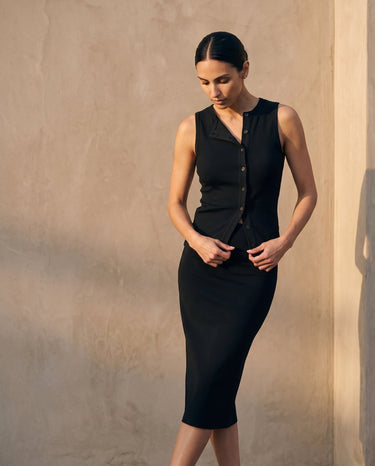 Model looking down in the black sleeveless top and skirt, full length – Moriel Heritage