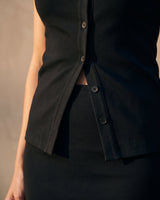 Close-up of the black top's stepped split hem and lower buttons – Moriel Heritage