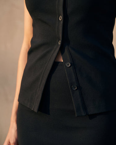 Close-up of the black top's stepped split hem and lower buttons – Moriel Heritage