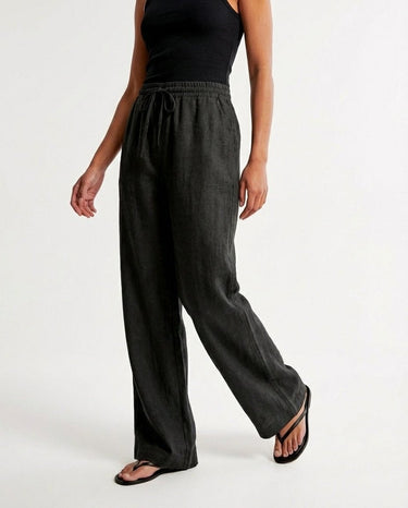 The Verena Cotton Linen Trousers in black — wide-leg trousers, walking view on model