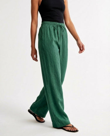 The Verena Cotton Linen Trousers in green — wide-leg trousers, walking view on model
