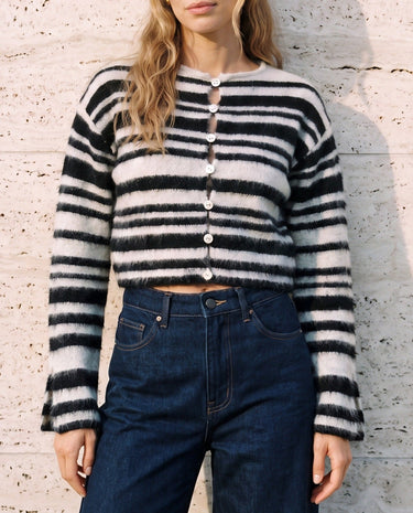 Tilia Knit Cardigan in white and black — cropped striped cardigan buttoned up with dark jeans, front view on model