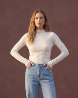 Model wearing pearl white mock-neck knit top, hands on hips front view – Moriel Heritage