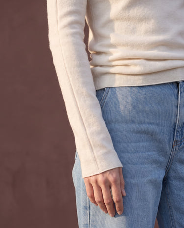 Close-up of pearl white knit top showing the fine knit and long sleeve over jeans – Moriel Heritage